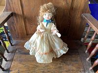 Front view of porcelain doll seated on wooden surface
