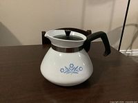 Full side view showing cornflower motif, handle, collar, lid