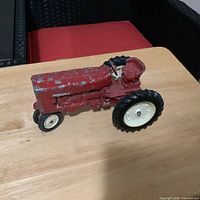 Side view of red cast metal tractor showing overall appearance and paint wear