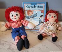 Raggedy Andy 20 in, Raggedy Ann 14 in, and hardcover book displayed upright