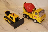 Tonka bulldozer and cement mixer truck side by side showing overall condition
