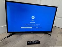 Front view of Samsung TV powered on displaying HDMI1 No Signal with remote in foreground