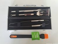 Open case displaying spatula, fork, tongs and separate basting brush