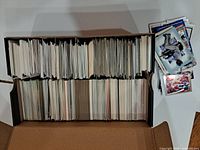 Open long black storage box filled with upright baseball cards