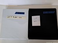 Closed white and black binders labelled Lot 7