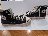 Full view of both sneakers side profile showing black uppers, white laces, rubber toe caps, soles