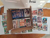 Open box filled with stacks of baseball cards; additional cards displayed in front
