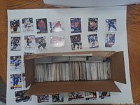 Open box filled with hundreds of hockey cards with sample cards displayed around it