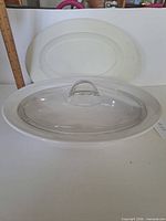 Dish with glass lid in front, plastic lid behind