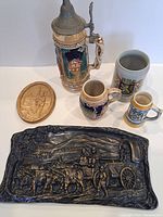 Group shot of all items: four steins, wood plaque, clay relief
