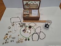 Overview of open jewelry box and spread of costume jewelry items with ruler