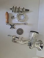 All components of Porkert No. 8 meat grinder laid out: auger, retaining ring, clamp screw, crank, knife, plate, main body