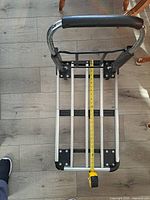 Top view of folded aluminum cart showing handle and platform with tape measure