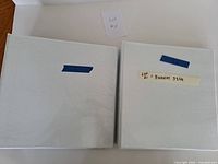 Two closed white binders front view