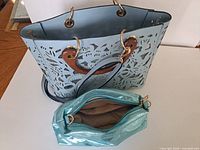 Top view of blue laser-cut tote purse and teal makeup bag showing size, design and interior