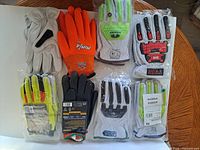 Eight packaged and loose work glove pairs laid out on table