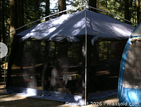 Erected blue screened shelter in forest setting, shows mesh walls and roof