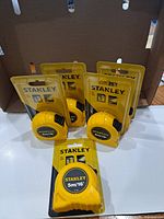Five sealed Stanley tape measures displayed upright and flat