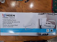 Retail box front showing Moen Home Care Toilet Safety Rails DN7015 and product image