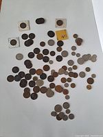 Full layout of approximately 70 mixed world coins spread on white background
