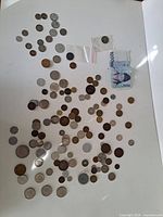 Spread of approximately 95 coins and 2 banknotes on white background