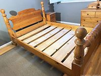 Full view of assembled queen solid wood bed frame showing headboard, footboard, side rails and slats