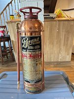 Full view of copper Pyrene soda-acid fire extinguisher with hose and label visible