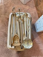 All six brass fireplace tools laid out in bin showing full length