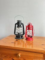 Black and red metal hurricane lanterns on wooden surface