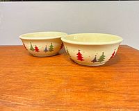 Pair of matching cream stoneware bowls showing exterior festive tree design
