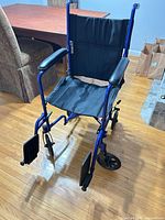 Full view of blue collapsible wheelchair with footrests attached
