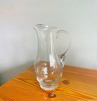 Full view of clear glass pitcher on wooden surface