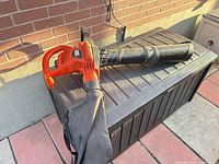 Full view of Black+Decker orange leaf vacuum on storage box