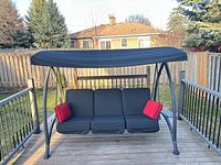 Full view of porch swing on deck showing canopy and frame