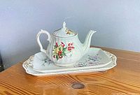 Teapot positioned on matching floral tray showing designs and condition