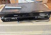 Front view of Toshiba VHS/DVD combo player with remote on top