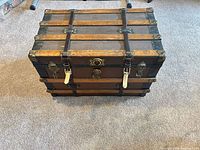 Closed steamer trunk showing top slats, straps, hardware