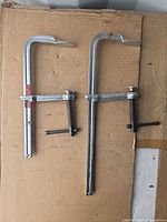 Full view of both metal F-clamps on cardboard