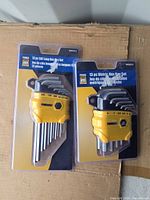 Both blister-packed PowerFirst hex key sets on cardboard background