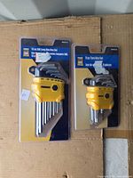 Both sealed PowerFist key sets on cardboard backing