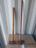 Both sledgehammers standing side by side showing relative lengths and overall condition