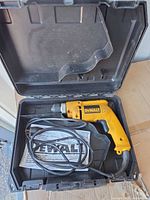 DeWalt corded drill in open case with manual and cord visible