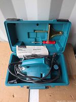 Open case displaying Makita planer, manual, guide fence, screwdriver