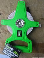Front view of green open reel tape measure showing tape and frame