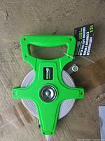 Front of green open-reel tape showing handle, hub and tag