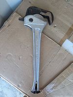 Full view of 18" aluminum pipe wrench on cardboard surface