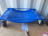 Top view of blue curved tire dolly on casters