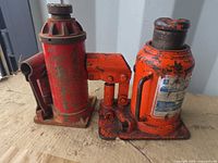 Both orange bottle jacks side by side on wooden surface