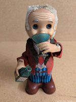 Full front view of tin toy man holding glass and bottle