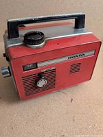 Front and side view of red Honda generator showing control panel and carry handle